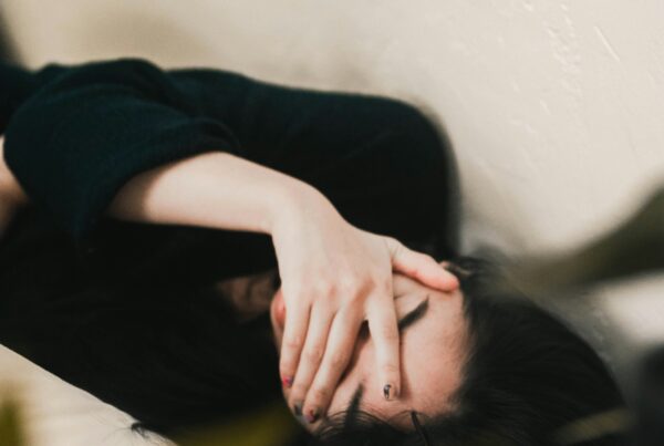 Exhausted woman resting with her eyes covered, a common sign of persistent low energy