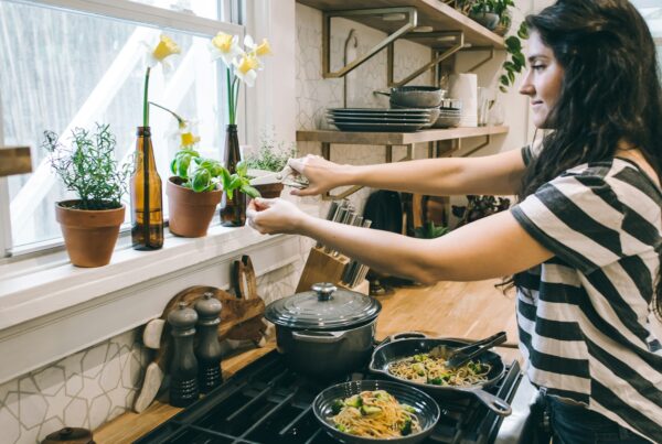 Woman preparing a protein-rich meal with vegetables, representing a PCOS and nutrition approach to managing symptoms